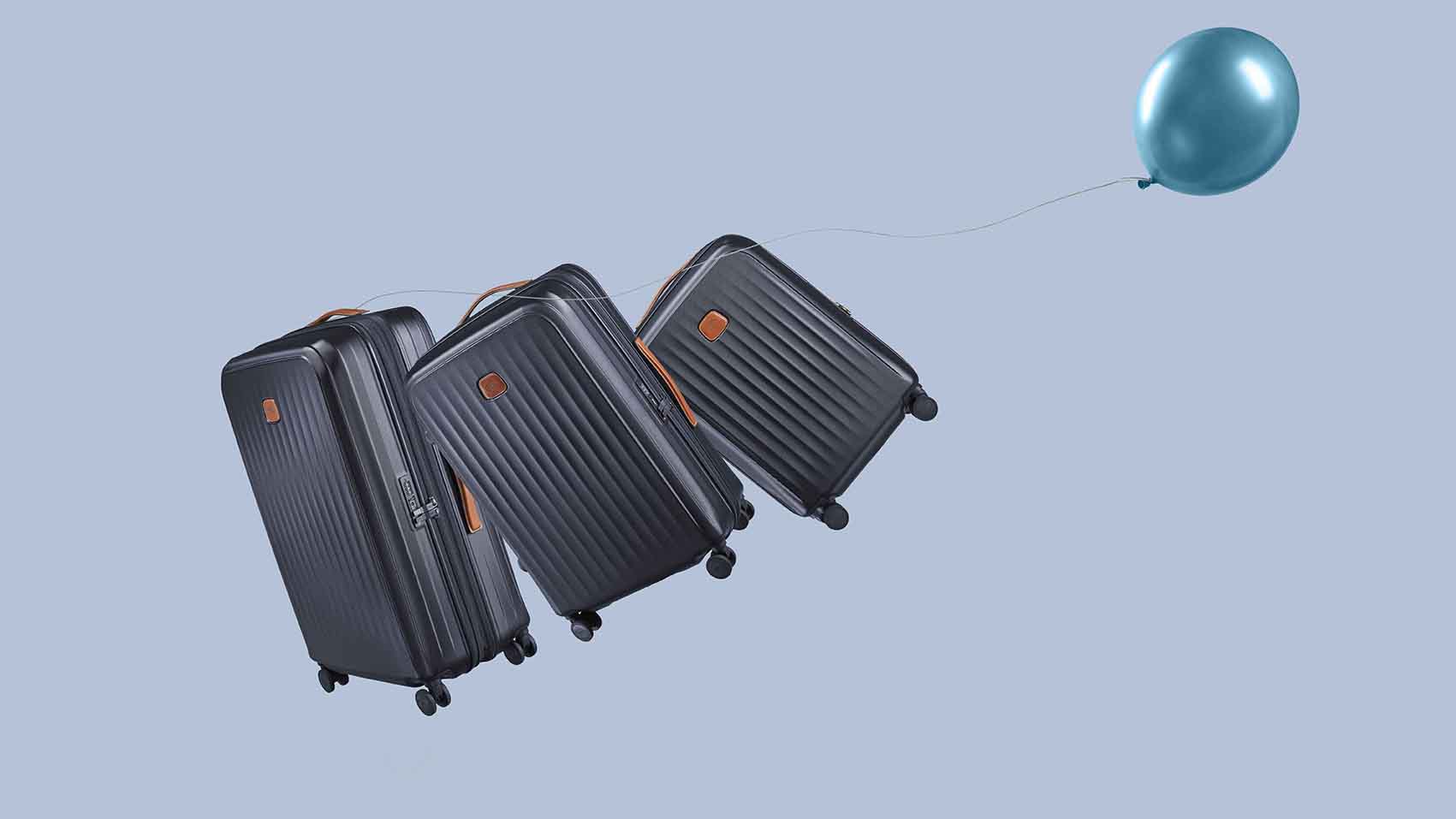 Lightweight hard-shell spinner luggage set in motion with a blue balloon, showcasing durable polycarbonate carry-on suitcases designed for effortless travel