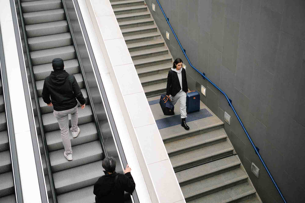 Business traveler carrying Bric's carry-on luggage through a modern transit station